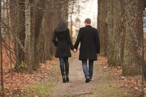 Husband and Wife holding hands walking through trees