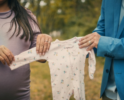 expectant parents holding baby onesie
