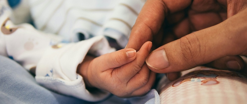 a newborn baby's hand being held by mothers hand